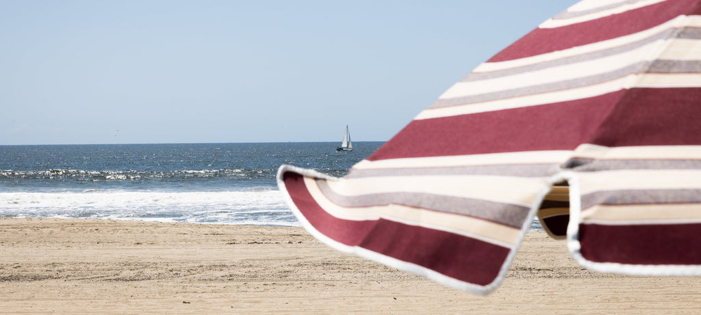 Beach umbrella on a sandy beach with ocean and clear sky in the background